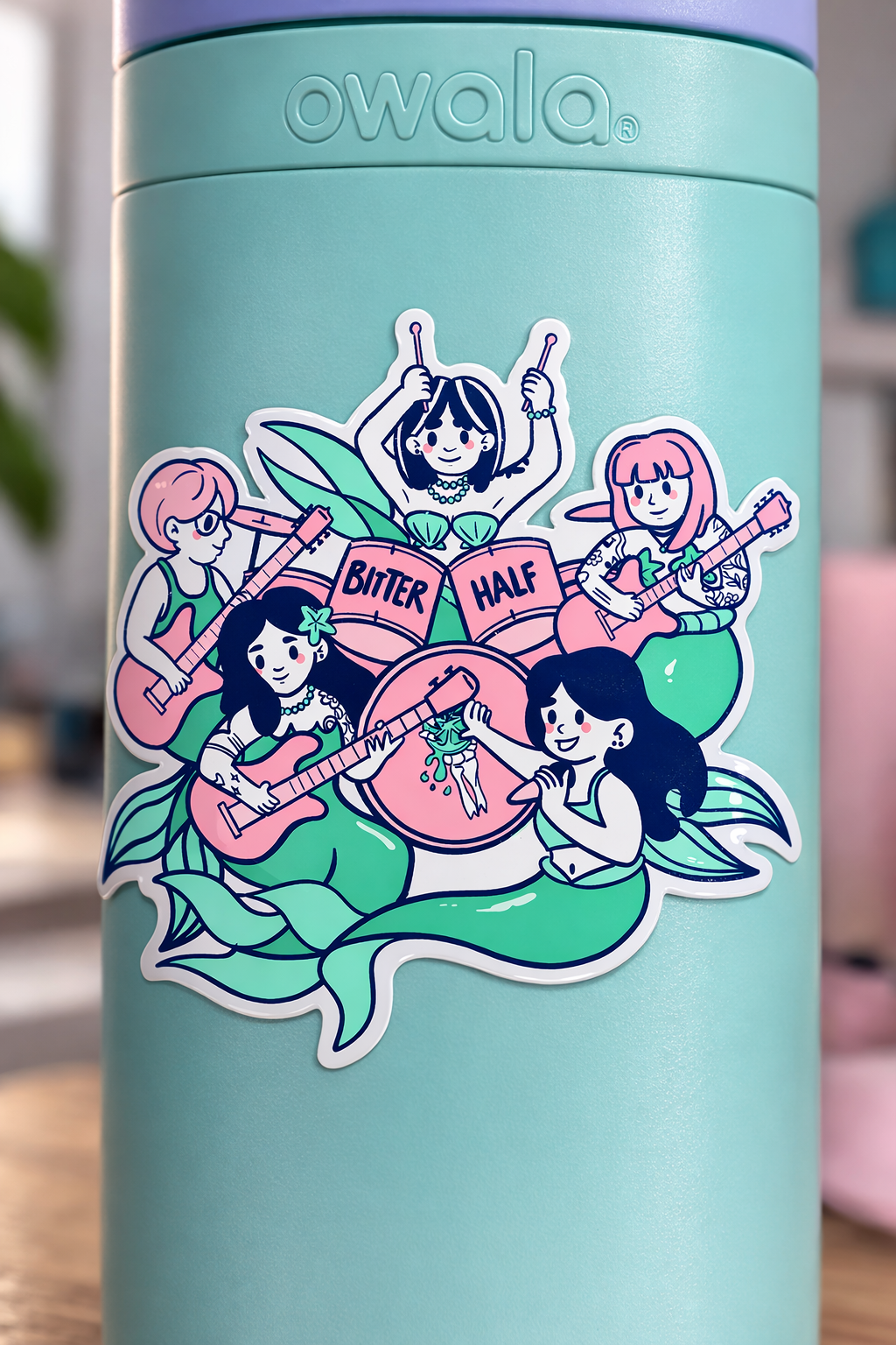 Teal water bottle with 'owala' branding and a colorful sticker featuring mermaid-like characters and the text 'Bitter Half'.